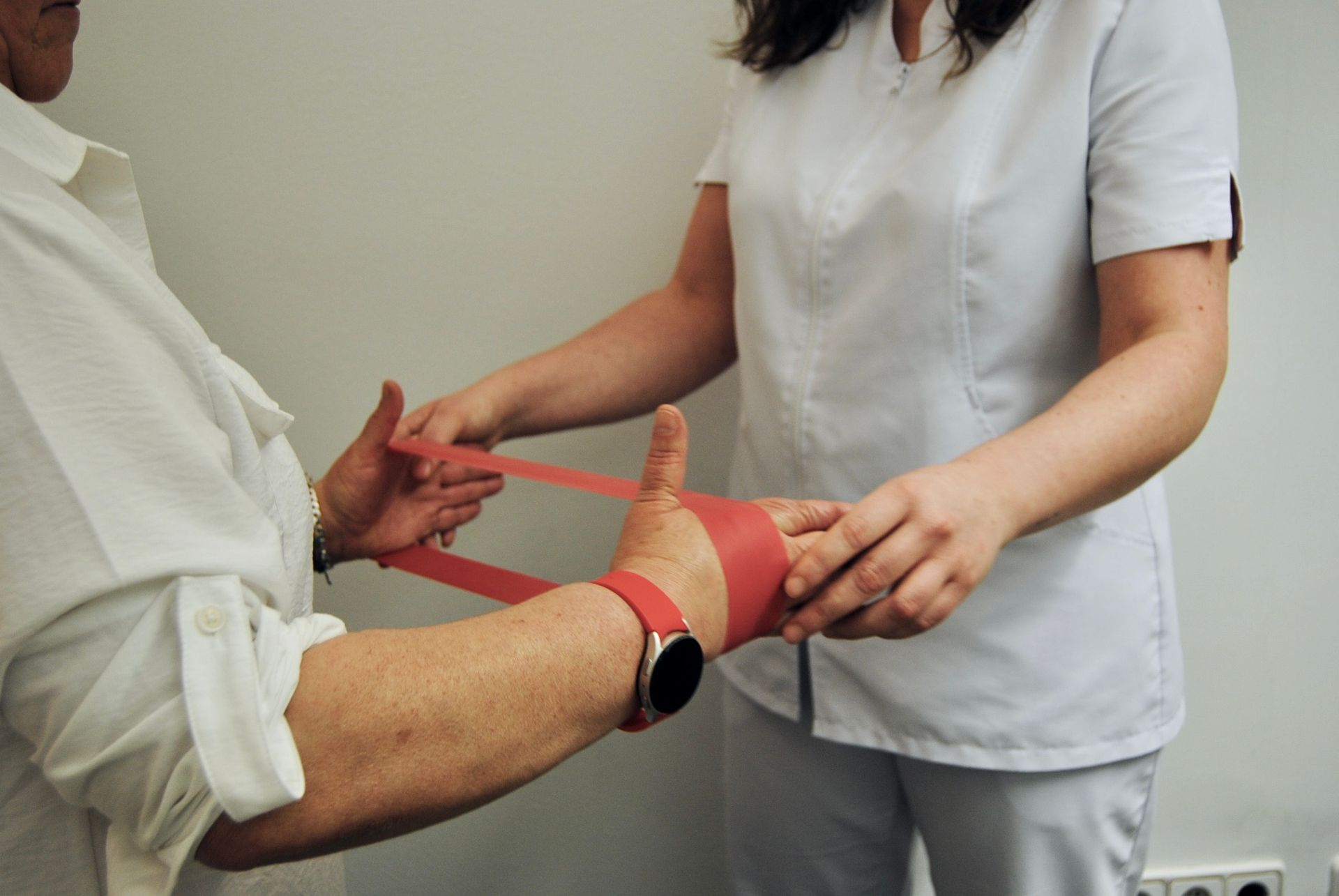 Una mujer está envolviendo la mano de un hombre con cinta roja.