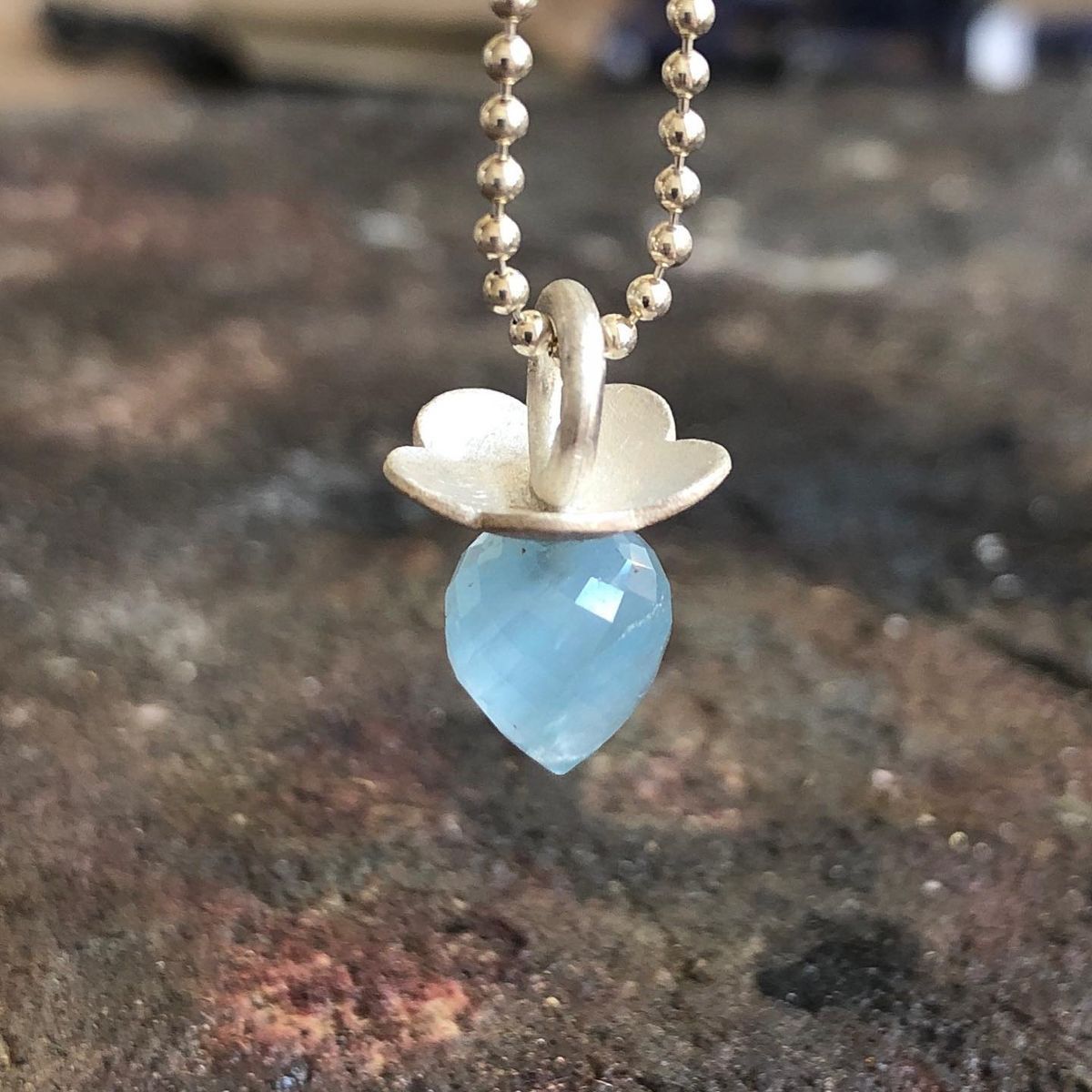 Eine Halskette mit einem blauen herzförmigen Anhänger an einer Kette