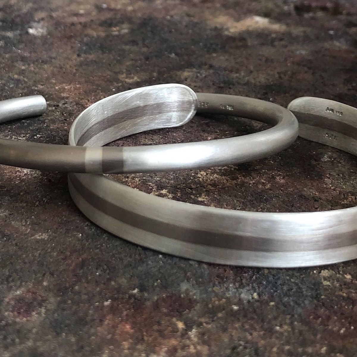 Ein Paar silberne Armbänder liegen auf einem Tisch.