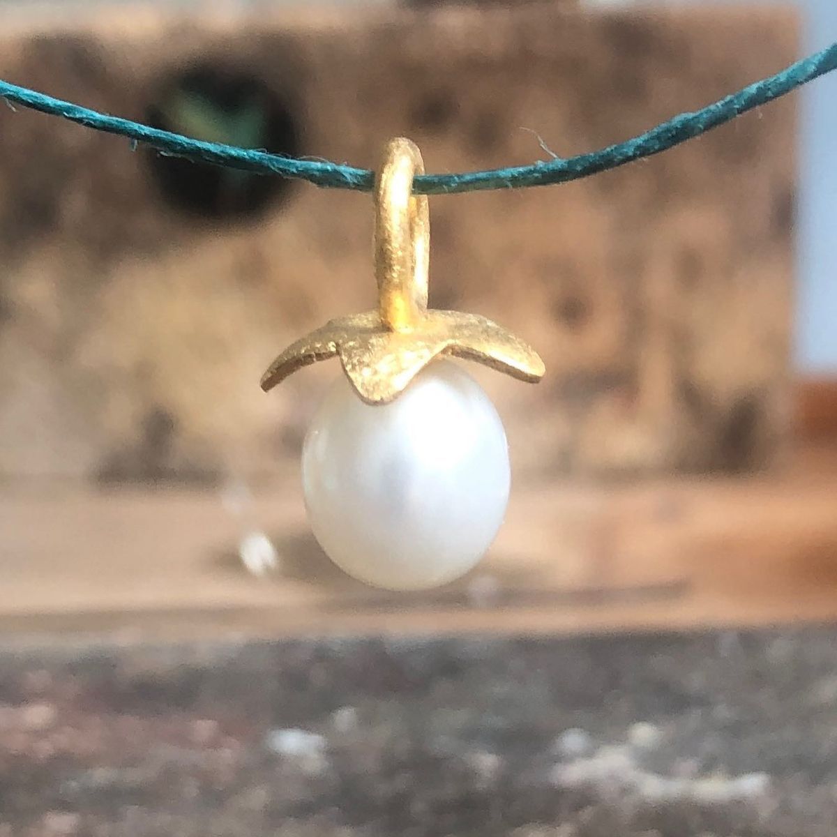 Ein goldener Anhänger mit einer weißen Perle darauf