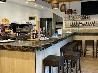Un bar con taburetes y botellas en la pared.