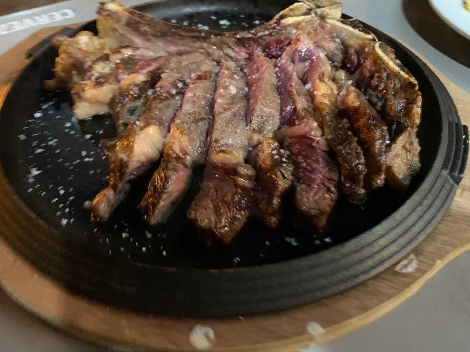 Un filete está sobre una sartén sobre una tabla de cortar de madera.