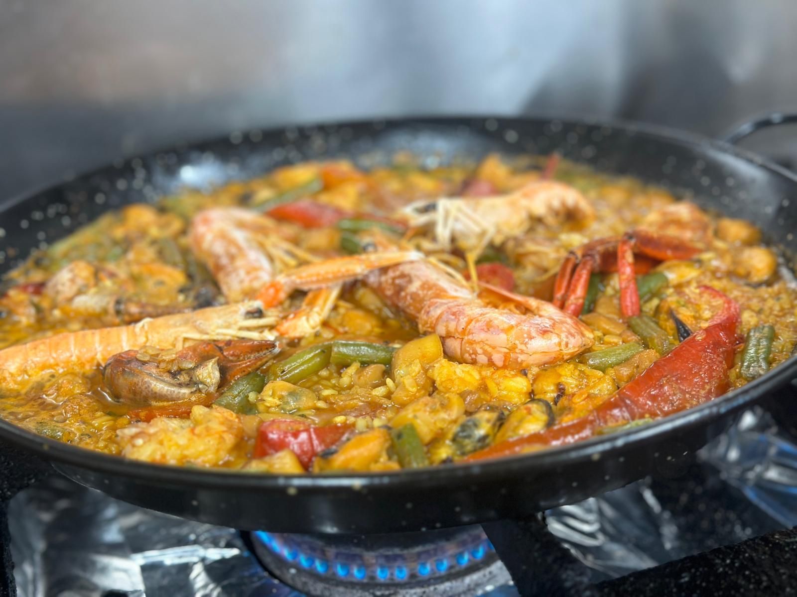 Una sartén llena de camarones y verduras se cocina en una estufa.