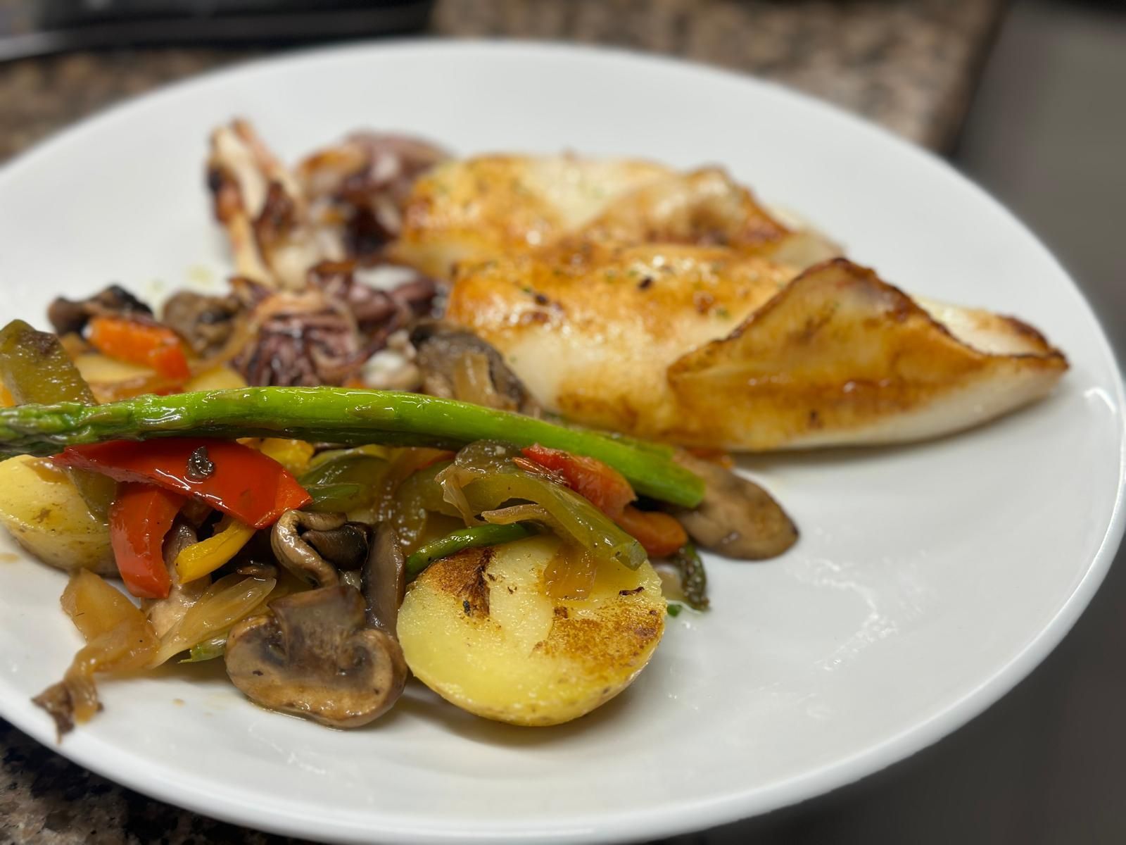 Un plato blanco cubierto con un trozo de carne y verduras.