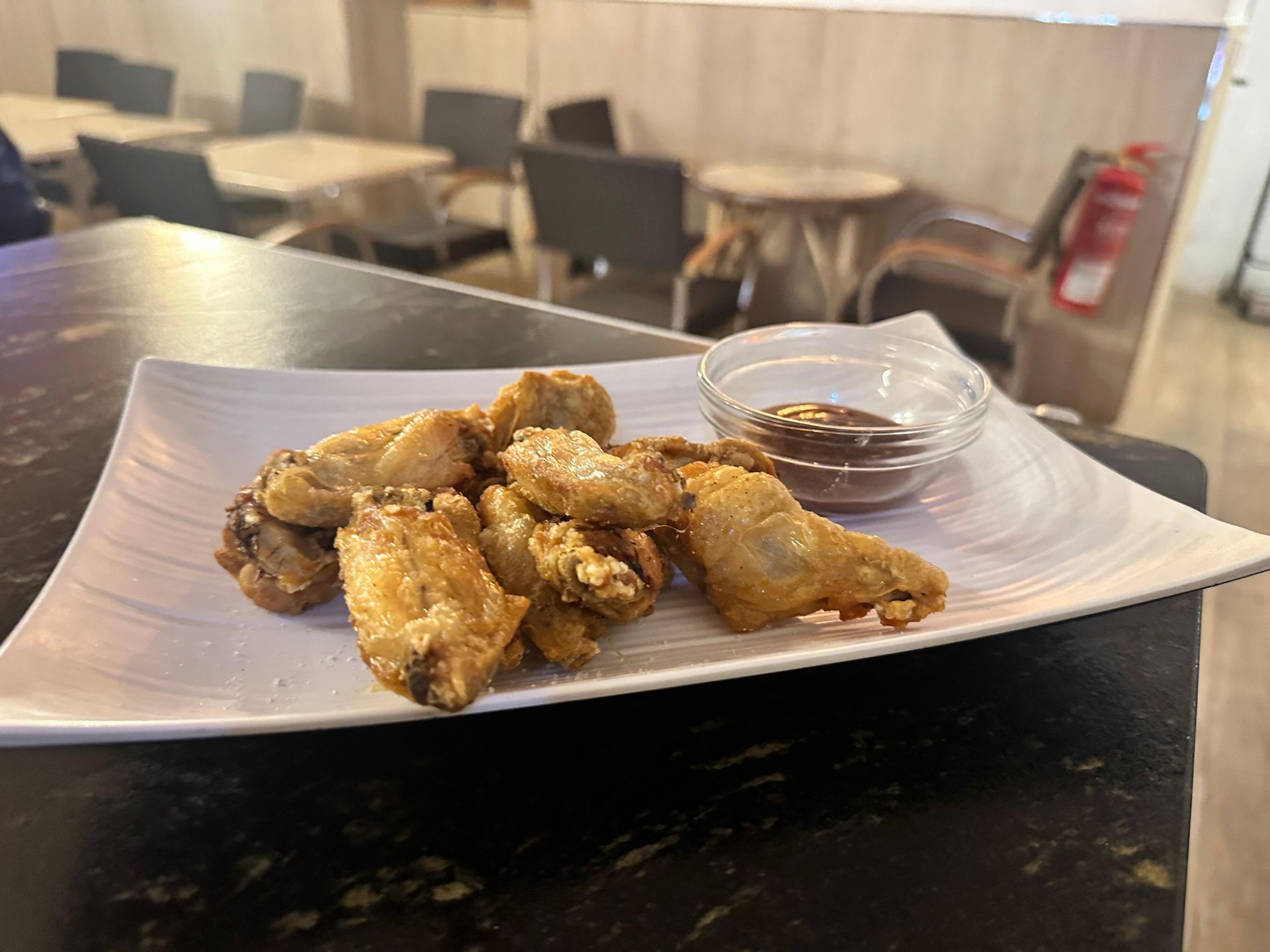 Un plato de alitas de pollo fritas con salsa para mojar en una mesa.