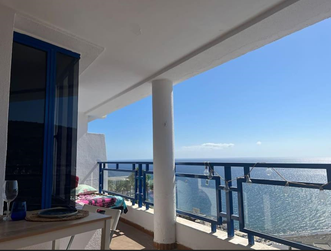 Un balcón con vista al mar con barandilla azul.