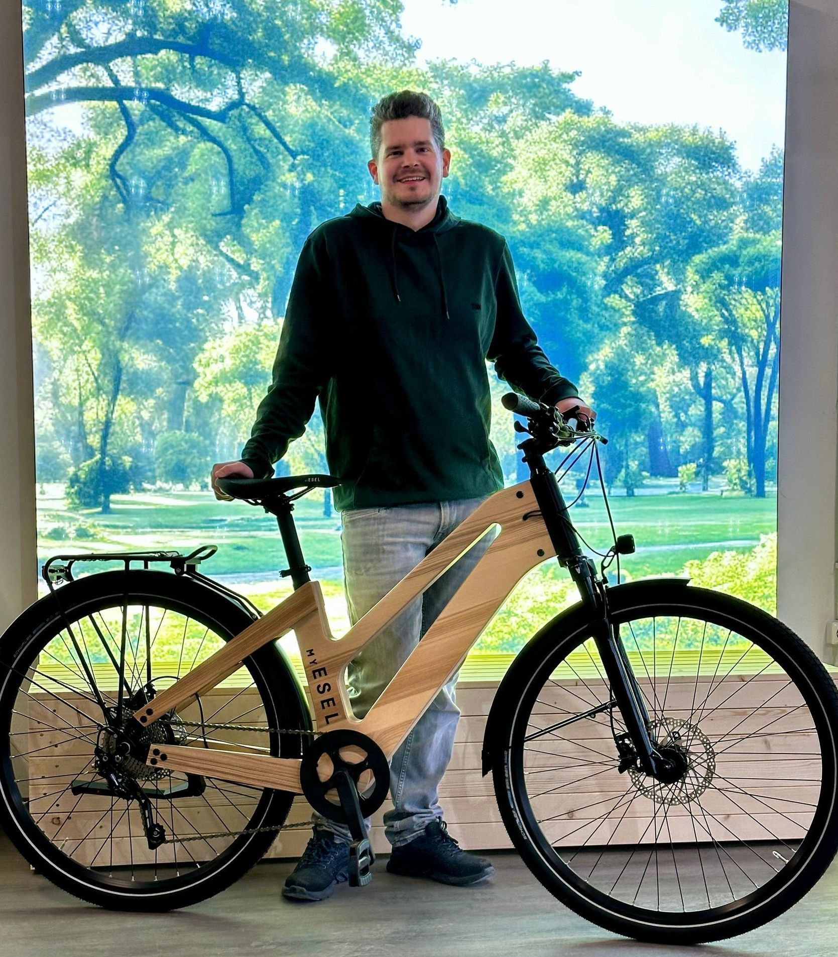 Ein Mann steht neben einem Holzfahrrad