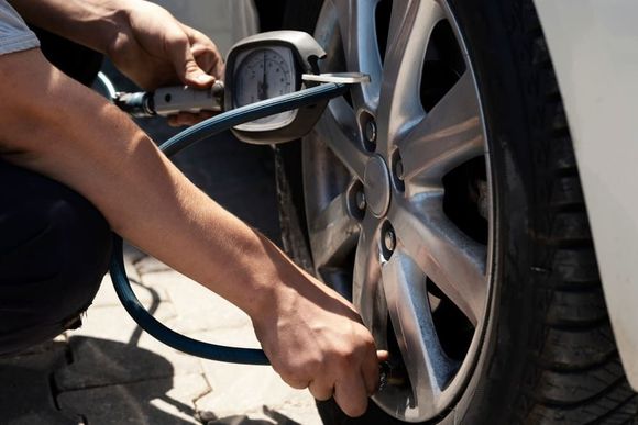 Persona inflando un neumático de automóvil con un compresor de aire, al aire libre.