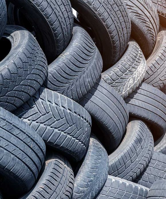 Pila de neumáticos de coche negros usados, con varios patrones de banda de rodadura visibles.