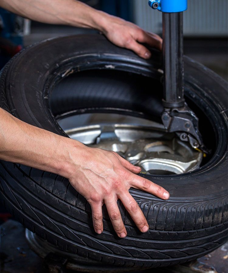 Manos trabajando en un neumático con una máquina en un taller de automóviles.