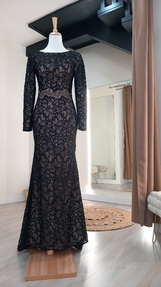 Un vestido de encaje negro está sobre un maniquí en un probador.