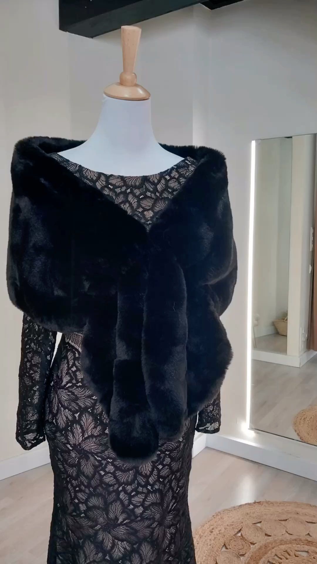 Un maniquí con un vestido de encaje negro y un chal de piel negro.