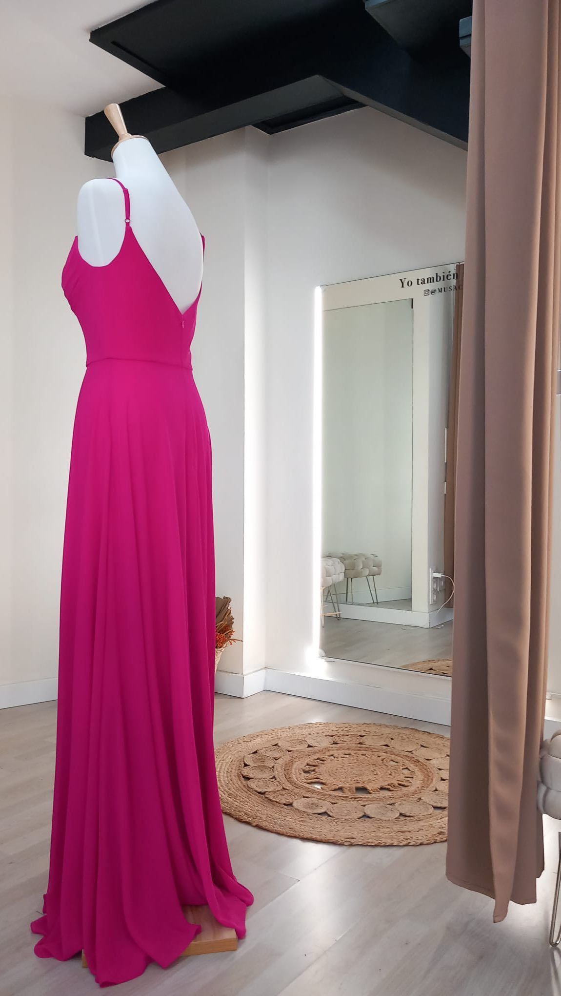 Un vestido rosa está sobre un maniquí en un probador.