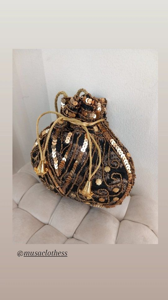 Un bolso negro y dorado reposa sobre un cojín blanco.