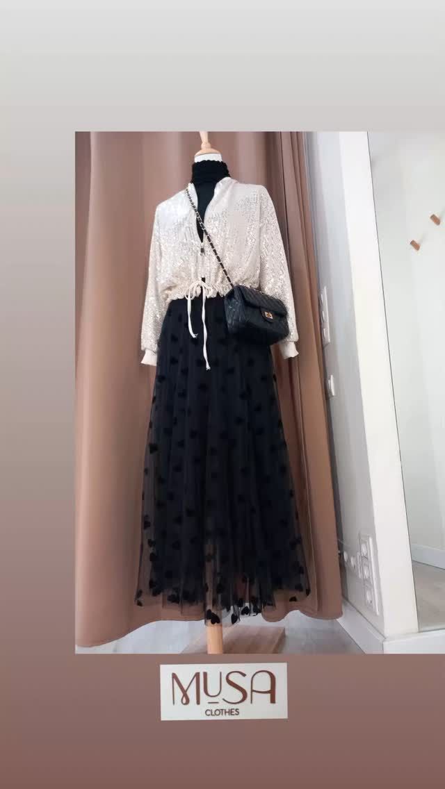 Un maniquí lleva una camisa blanca y una falda negra.