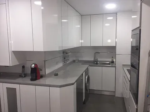 Una cocina con gabinetes blancos y electrodomésticos de acero inoxidable.