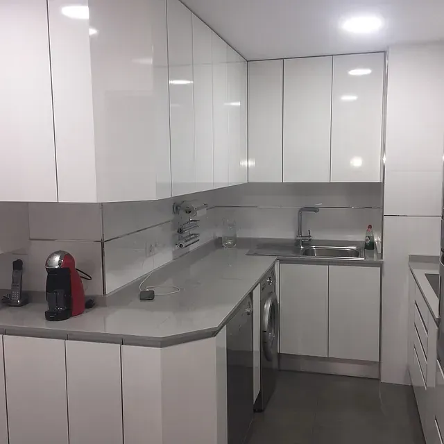 Reforma de cocina en Madrid con muebles blancos, encimera Silestone  y electrodomésticos de acero inoxidable.