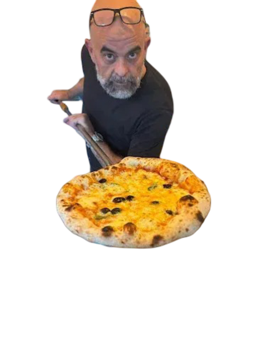 Un homme tenant une pizza, regardant le spectateur, dans une pizzeria. Four et comptoir visibles.