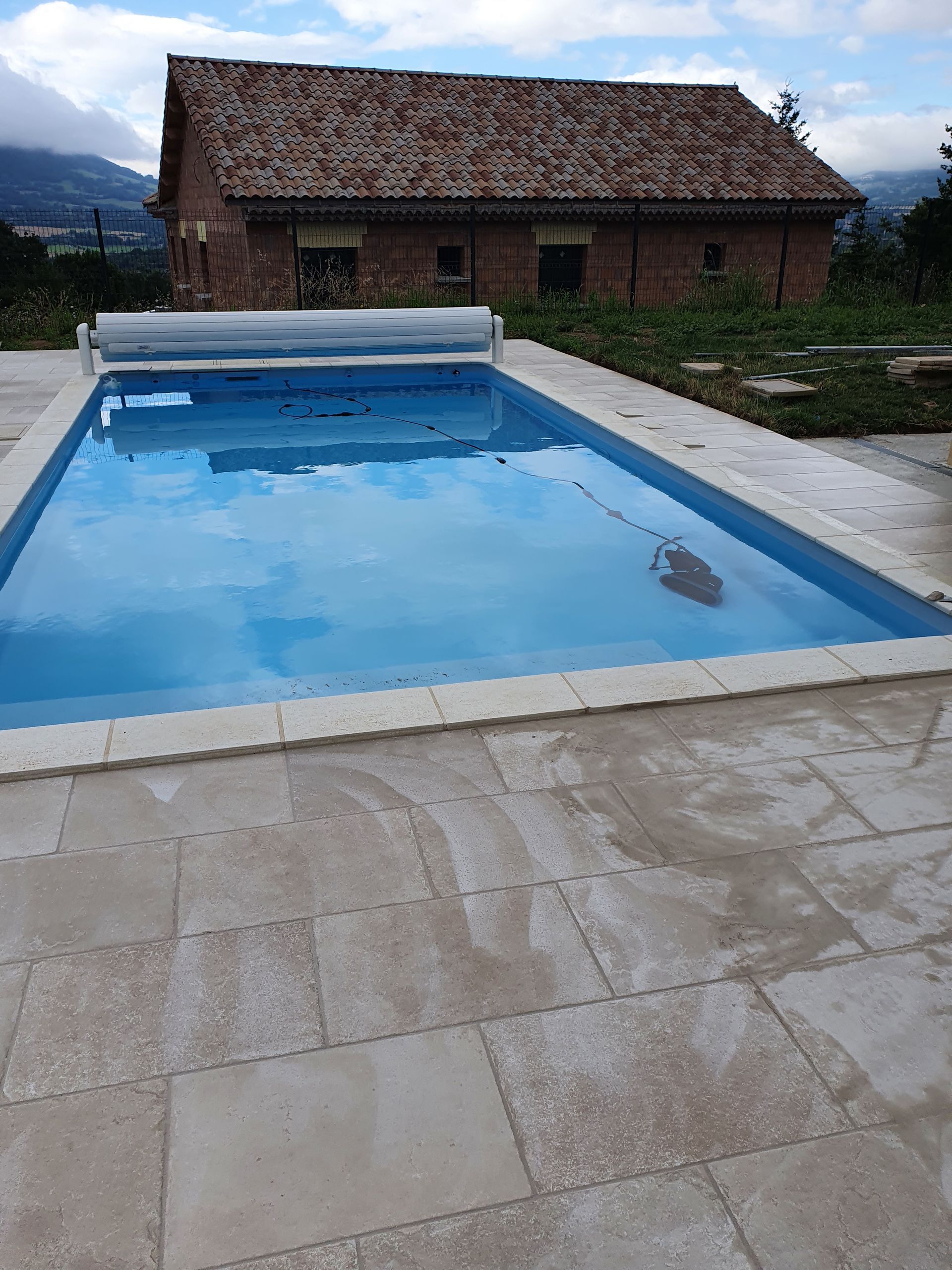 Une piscine en béton devant une maison.