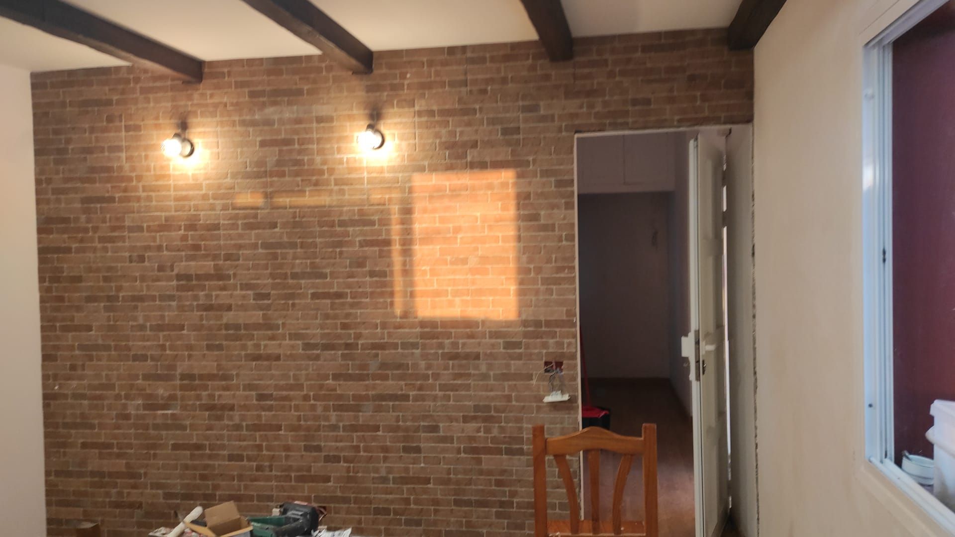 Una habitación con una pared de ladrillos y una silla de madera.