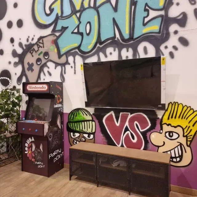 Una máquina de videojuegos Nintendo está frente a una pared que dice zona de juegos.