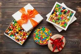 Una mesa de madera cubierta con cajas de dulces y un tazón de dulces.