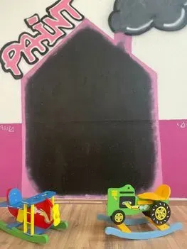 Dos juguetes mecedores frente a una pizarra que dice pintar