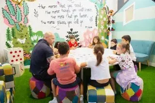 Un grupo de niños está sentado alrededor de una mesa jugando un juego.