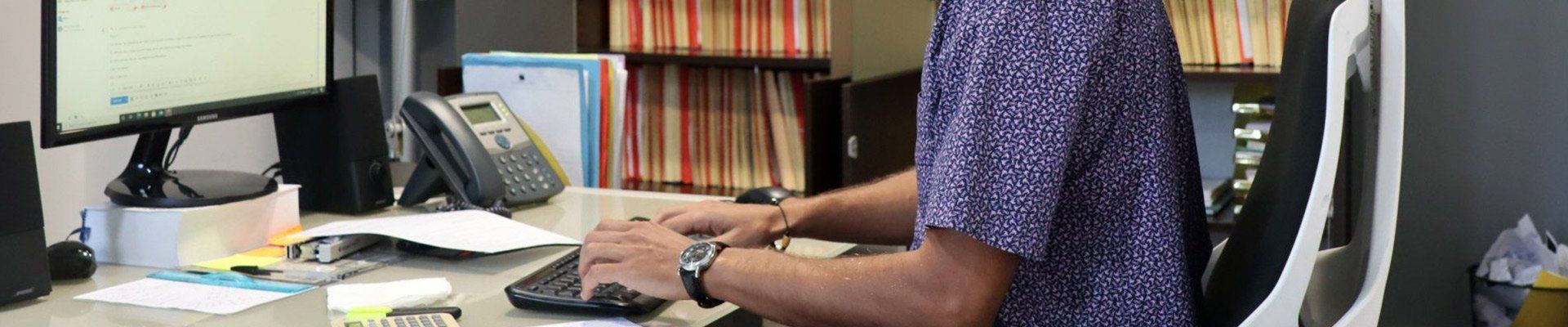 Homme à son bureau avec une chemise violette et blanche et une montre noire