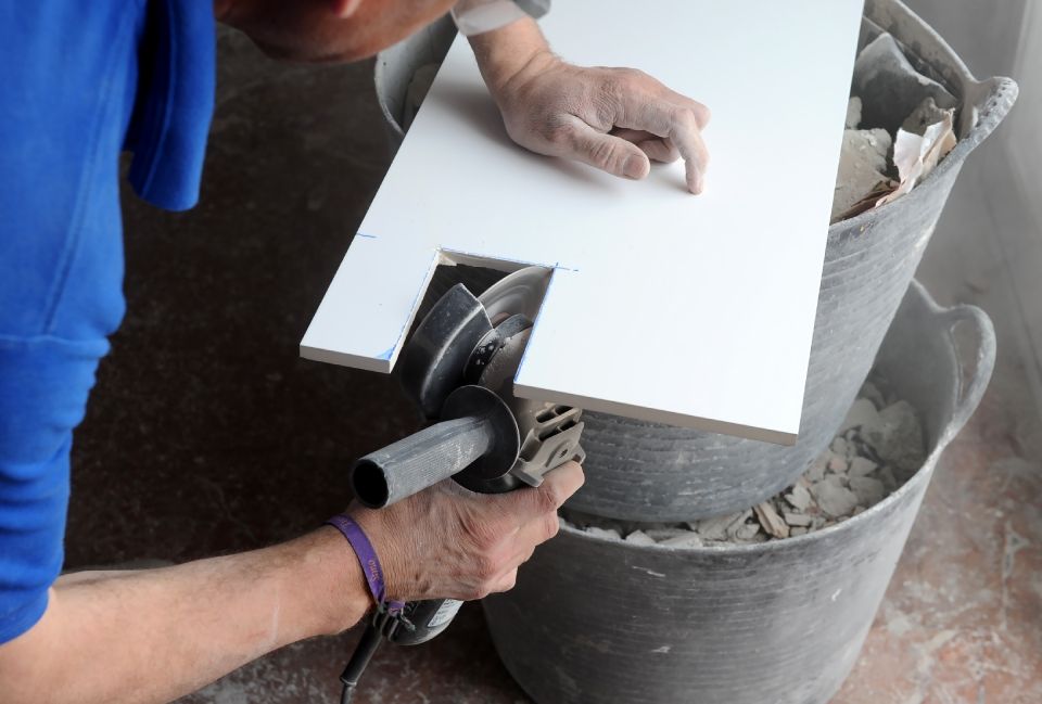 Fliesenleger Dieter Höpner schneidet eine Fliese aus