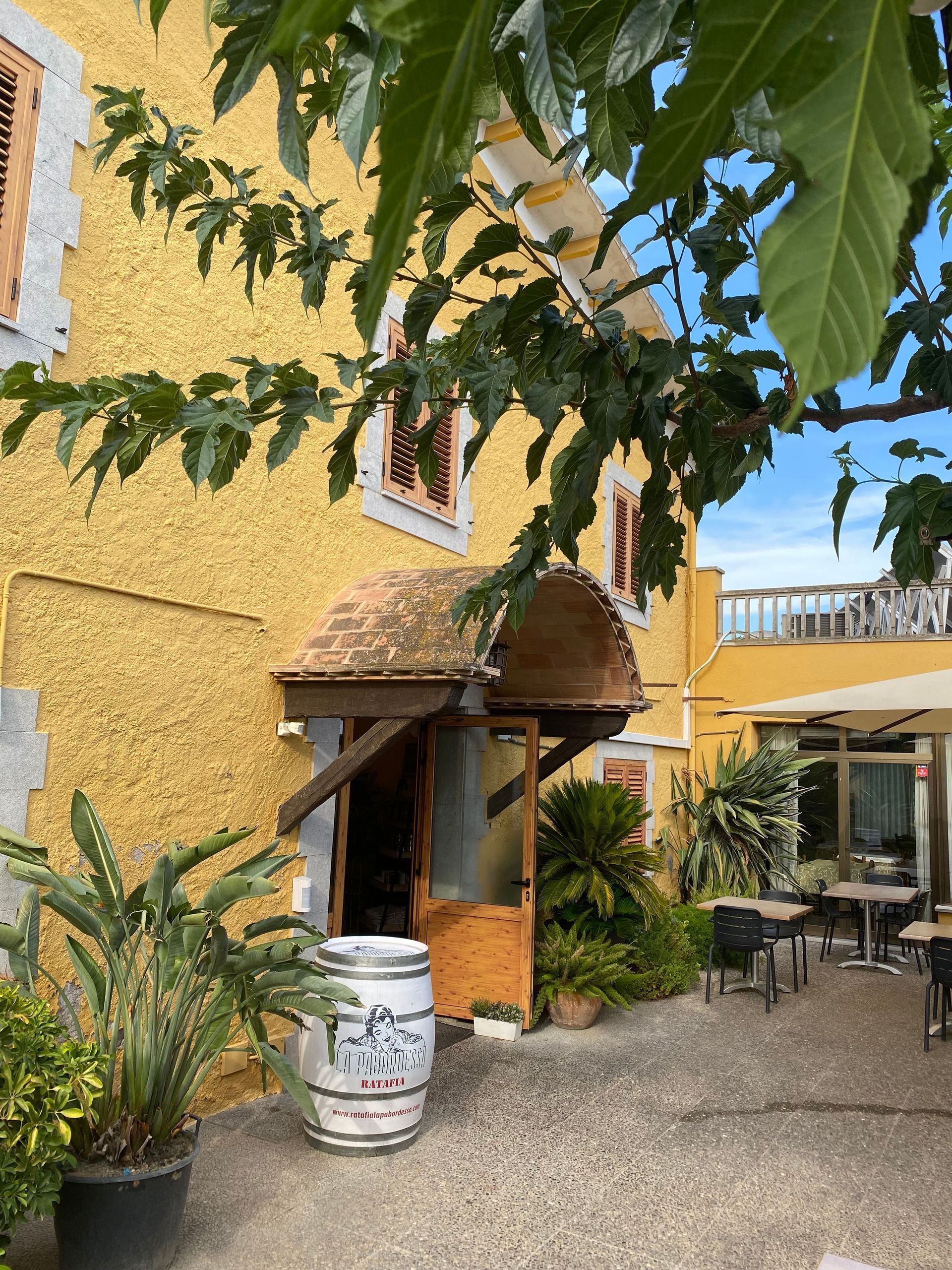 Un edifici groc amb un barril blanc al davant.