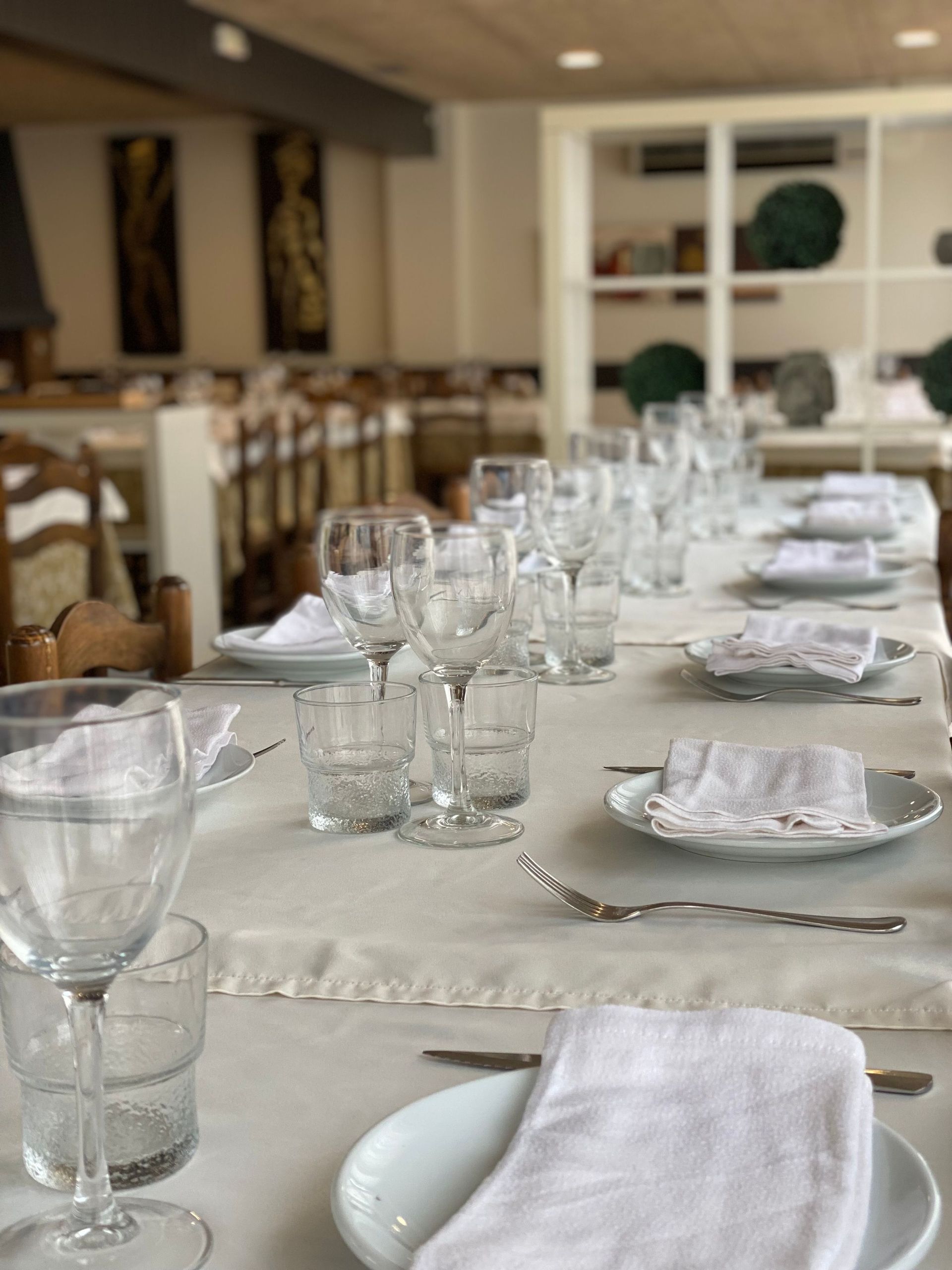 Una taula llarga amb plats, gots i tovallons en un restaurant.