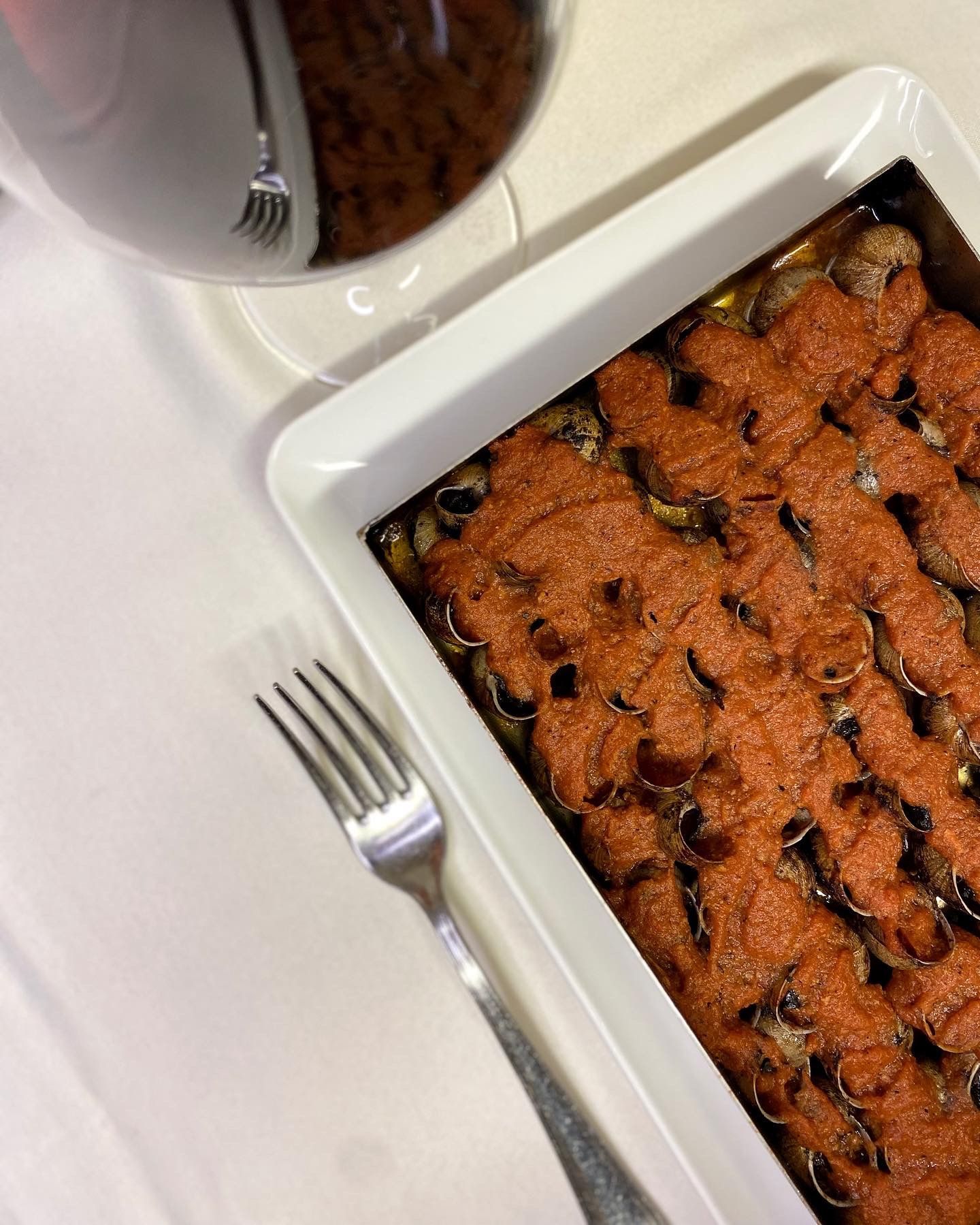 Una cassola amb una forquilla al costat d'una copa de vi