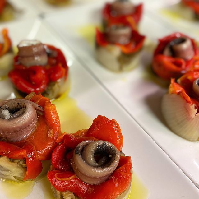 Un plat blanc amb pebrots vermells i anxoves