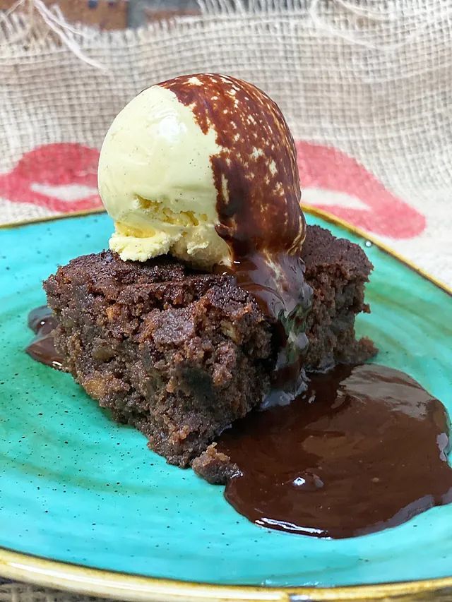Un brownie amb gelat a sobre en un plat blau.