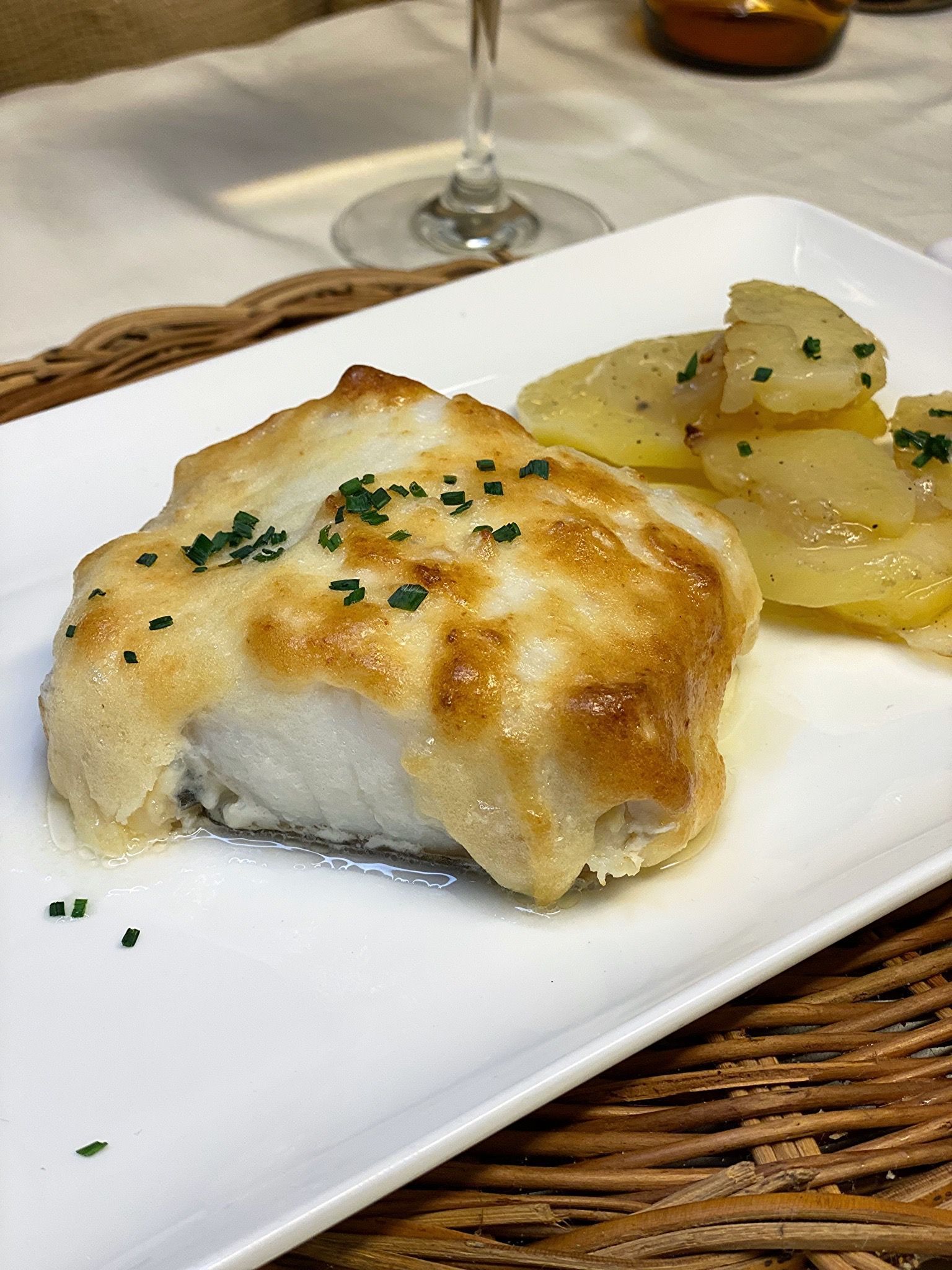 Un plat blanc amb un tros de peix i patates a sobre.