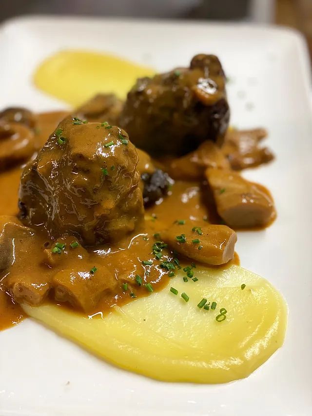 Primer pla d'un plat de menjar amb puré de patates i salsa sobre una taula.