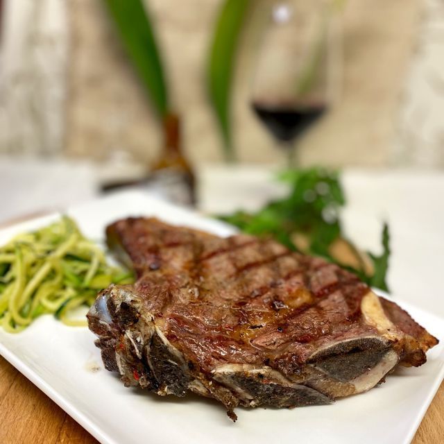 Un plat blanc amb un bistec i fideus de carbassó cobert