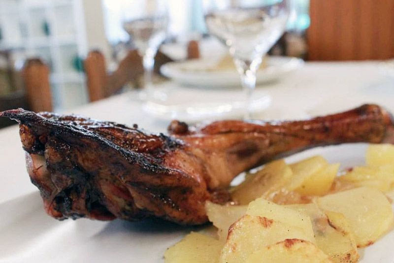 Un plat blanc amb carn i patates sobre una taula.