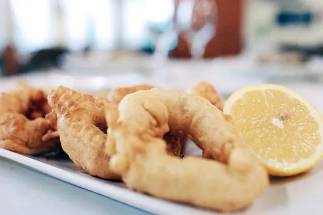 Un plat blanc amb calamars fregits i una rodanxa de llimona.