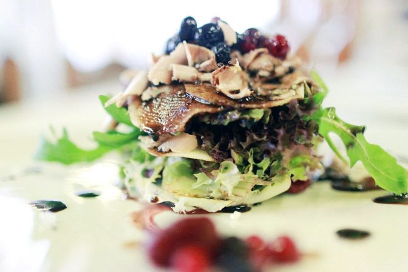 Primer pla d'una amanida amb baies a sobre en un plat blanc.