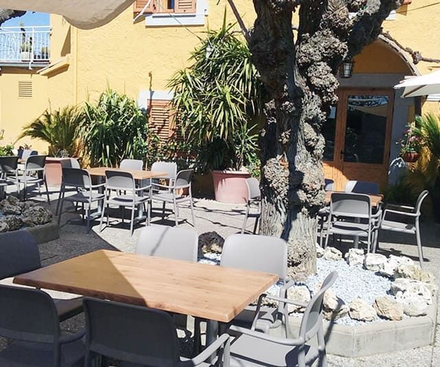 Un pati amb taules i cadires davant d'un edifici groc