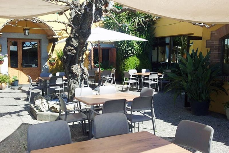 Una zona de pati amb taules i cadires sota para-sols