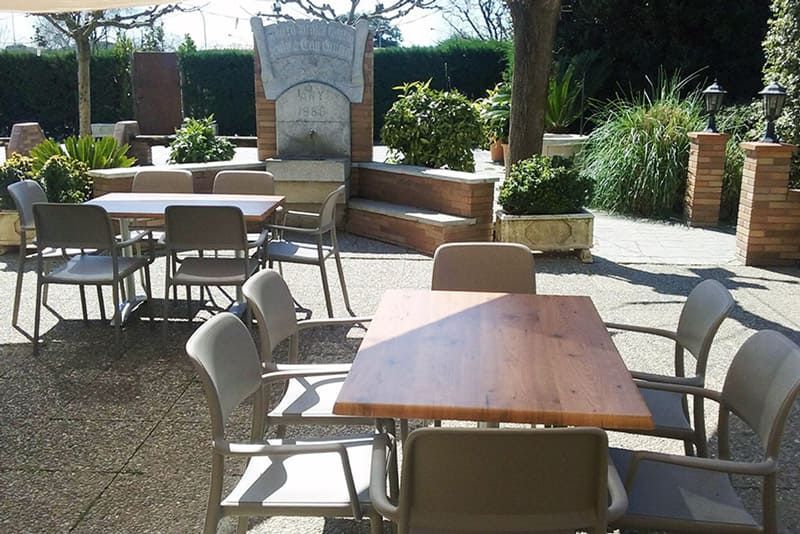 Un pati amb taules i cadires i una font al fons