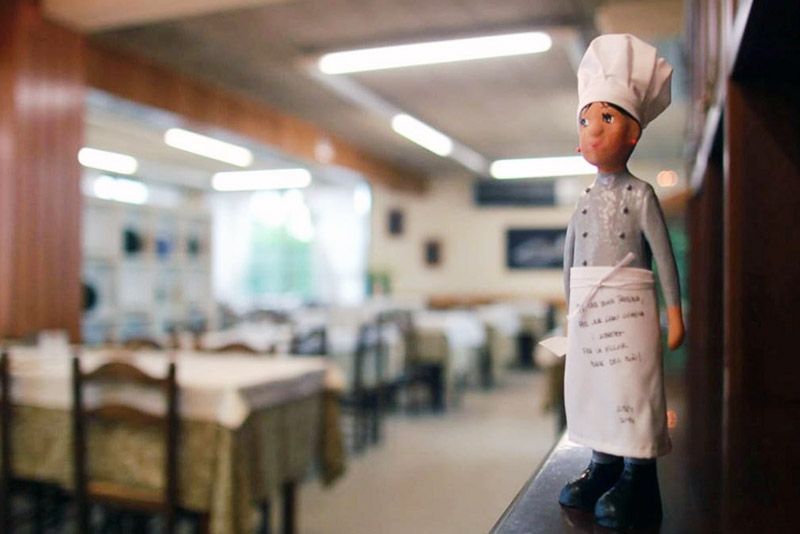 Una figureta d'un xef en un restaurant amb taules i cadires al fons