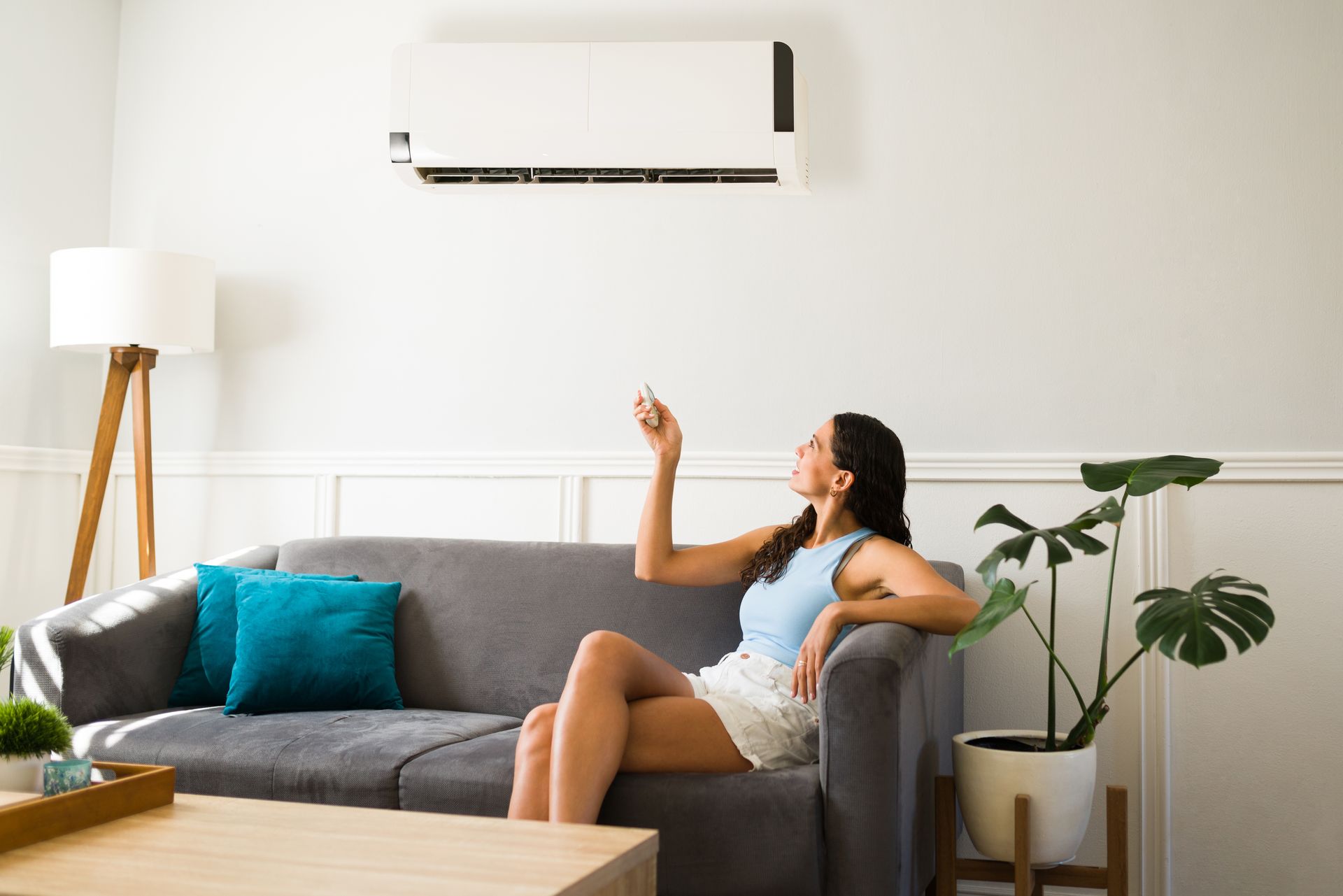 Une dame tient une télécommande vers le climatiseur