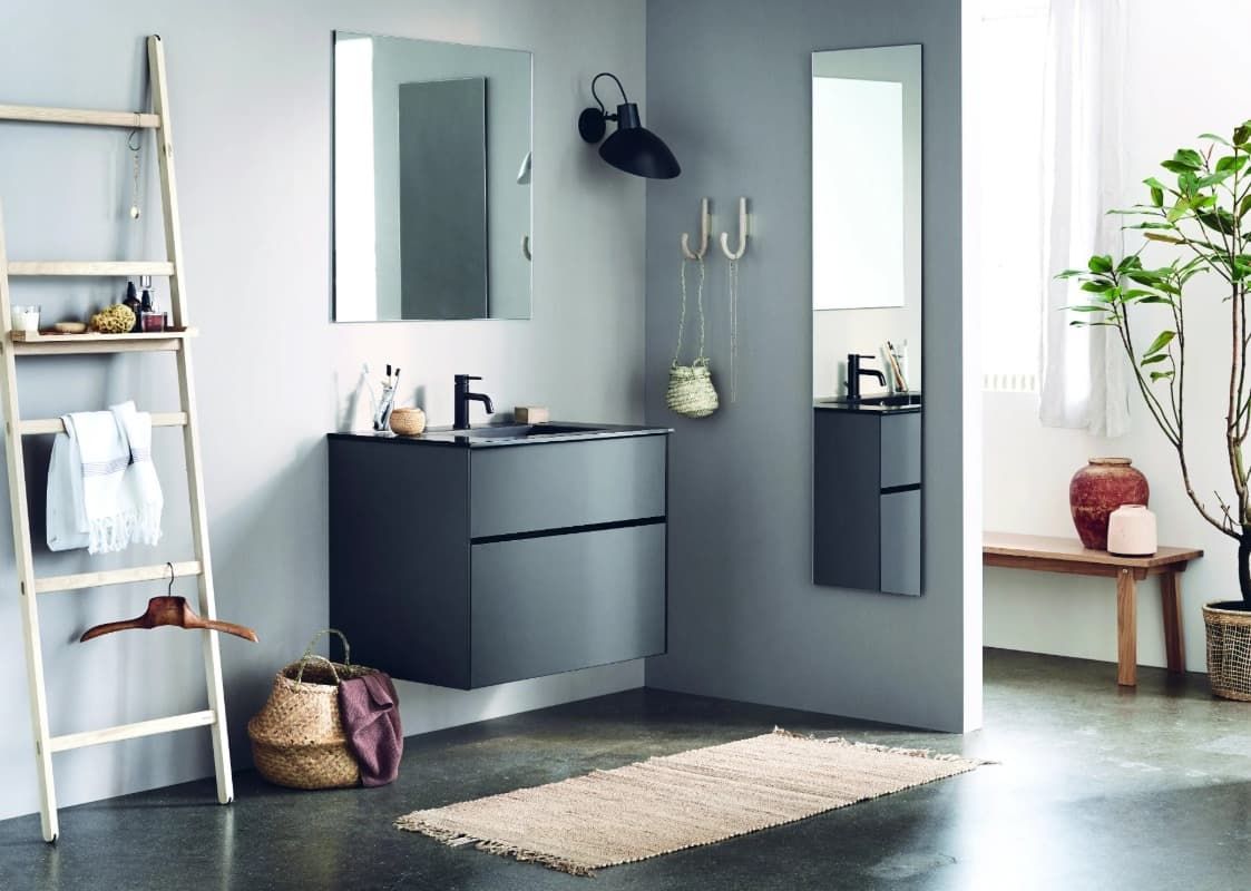 Baño con tocador gris, espejos, estante de escalera de madera, plantas y alfombra.