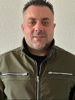 Mann mit verschränkten Armen steht vor einer Tür mit der Aufschrift „Privat – Kein Zutritt“. Er trägt eine braun-graue Jacke.