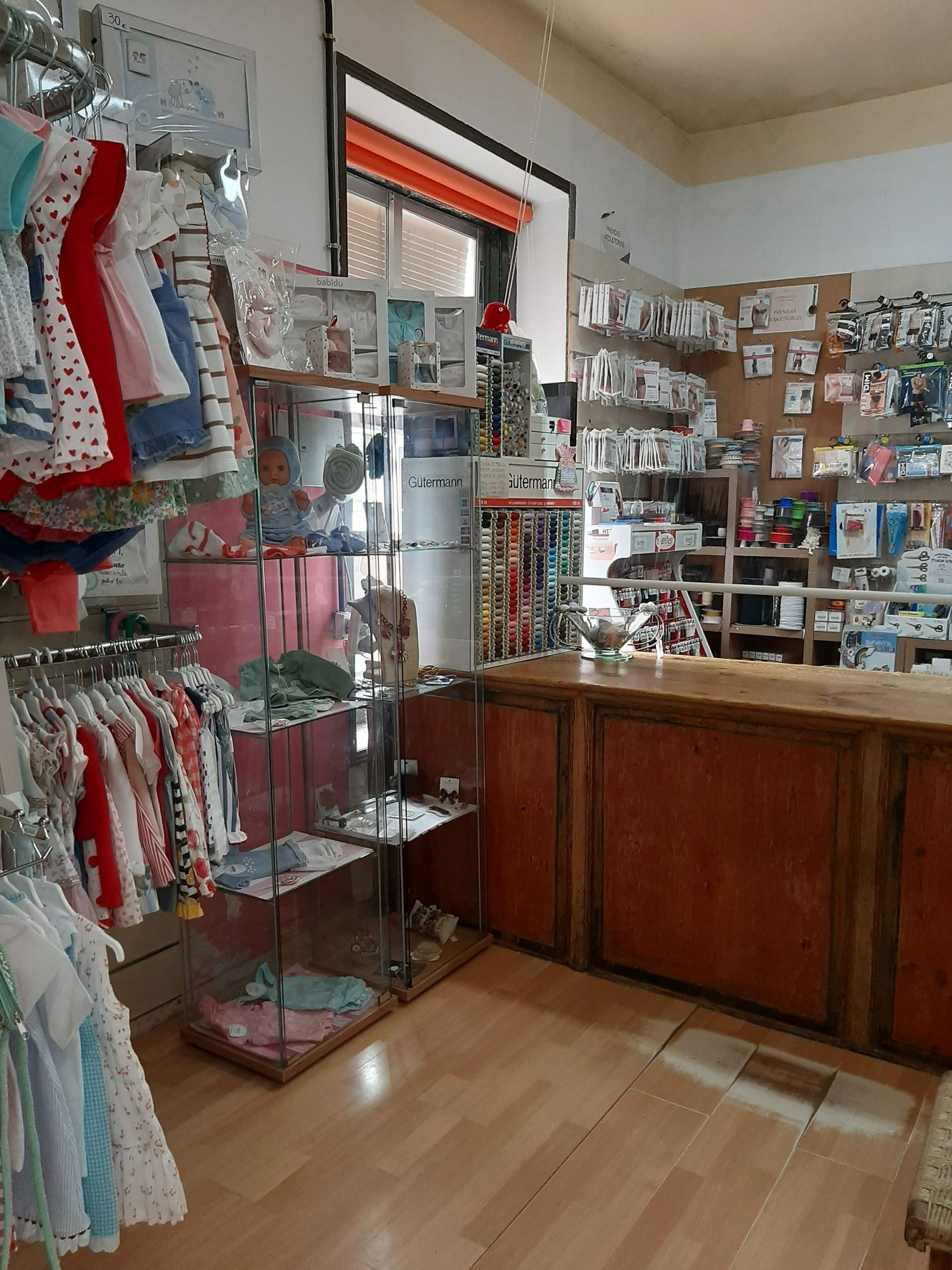 Una tienda llena de mucha ropa y un mostrador.