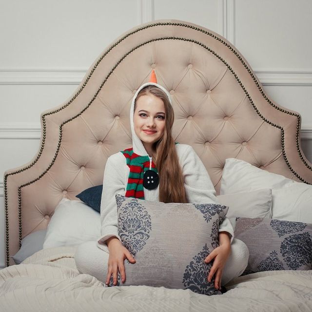 Una mujer está sentada en una cama sosteniendo una almohada.